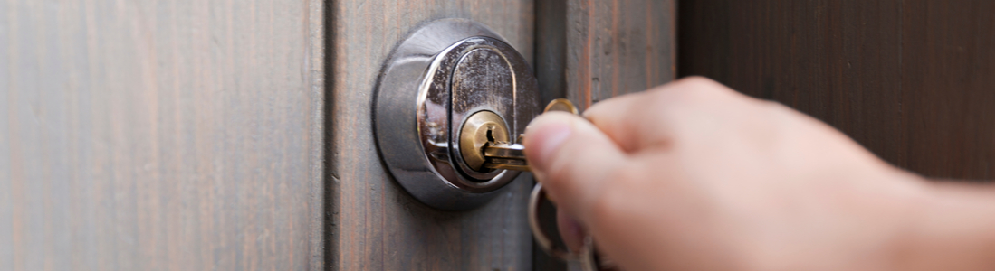 A hand unlocking a front door.