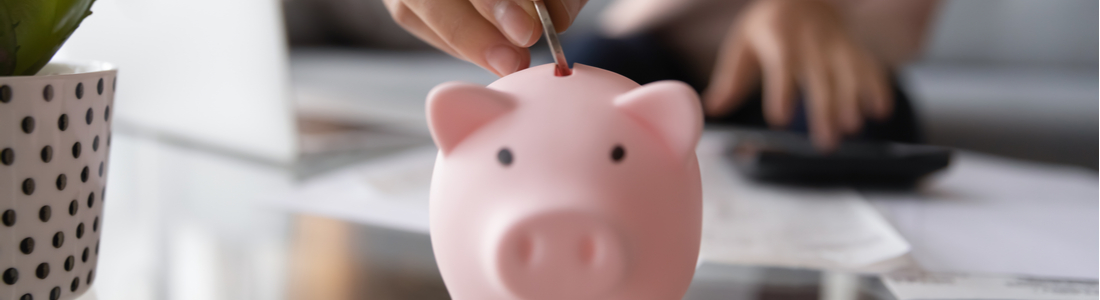 A woman placing money in a piggy bank.