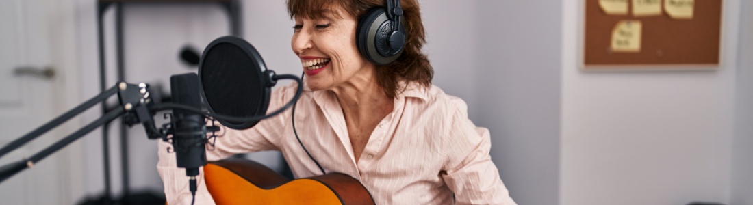 A woman playing a guitar in a music studio.