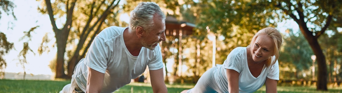 A couple doing yoga in a park.