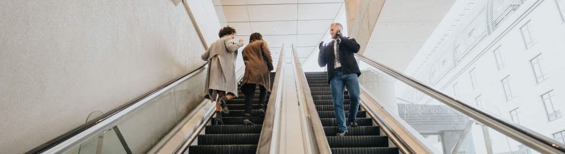 People using escalators in an office building.