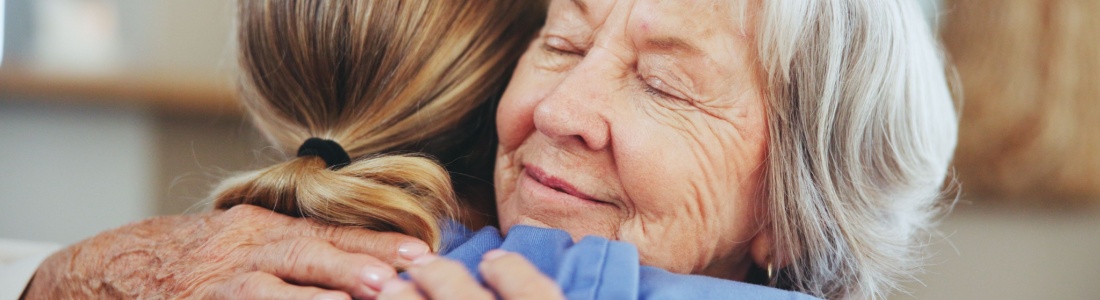 A senior woman hugging a caregiver.