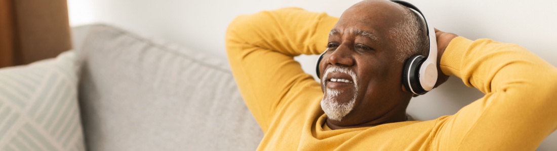 A man relaxing on a sofa with his hands behind his head.