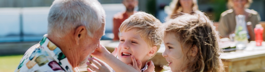 A grandfather playing with his grandchildren outdoors.