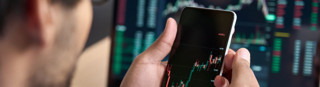 A man looking at a graph showing stock market performance on his phone.