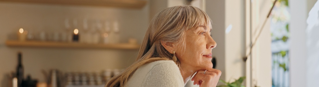 A woman looking out of the window at home.