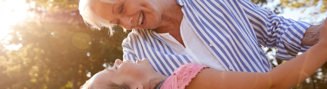 A grandmother playing with her granddaughter outside.