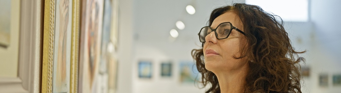 A woman looking at a painting in an art gallery.
