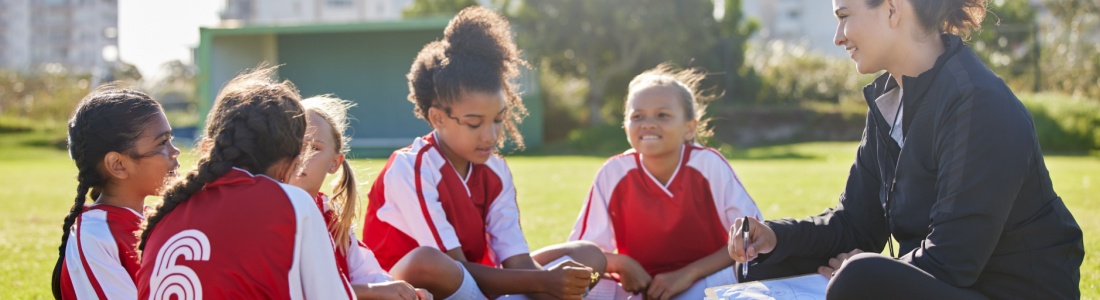 A woman coaching a girl’s football team.