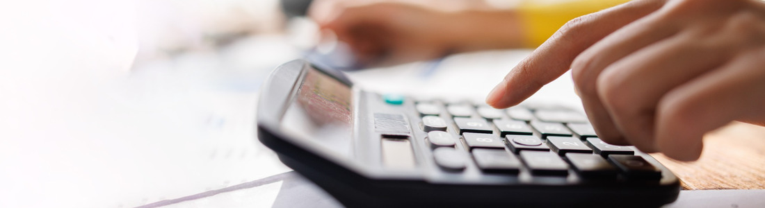 A person using a calculator while reviewing paperwork.
