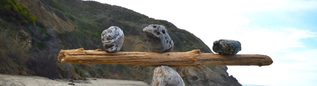 Rocks balancing on log on top of another rock